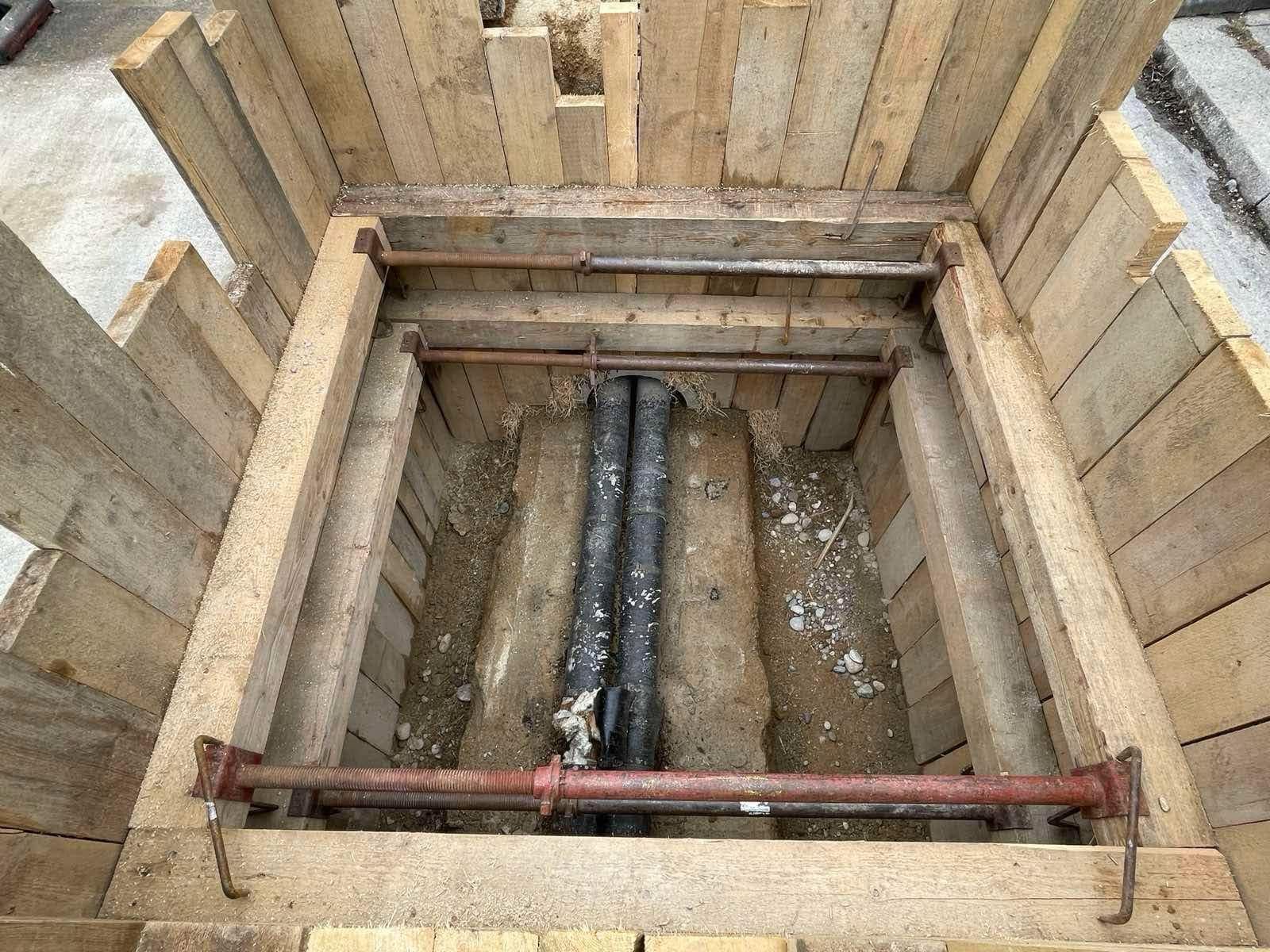 Verbauter Rohrgraben mit Holzverbau und erdverlegter Leitung